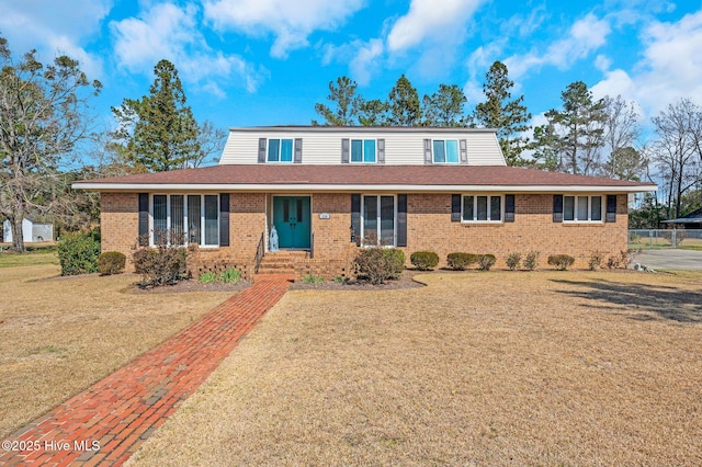 view of front of property with a front yard, brick siding, and roof with shingles