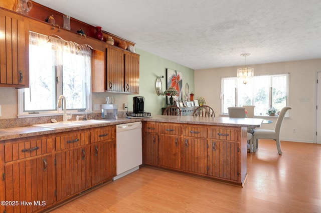 kitchen with a sink, dishwasher, a peninsula, and brown cabinetry