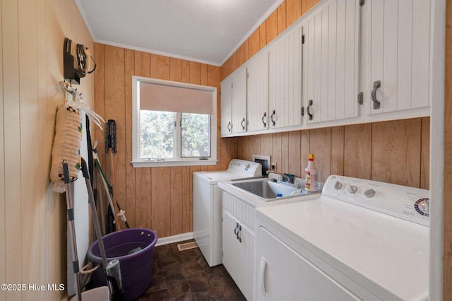 washroom featuring cabinet space, separate washer and dryer, a sink, wood walls, and crown molding