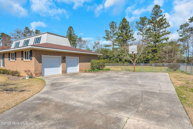 view of home's exterior with concrete driveway, fence, brick siding, and a lawn