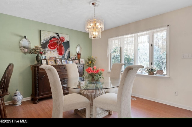 dining area with a chandelier, baseboards, and wood finished floors