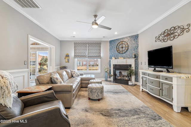 living room with ceiling fan, visible vents, and ornamental molding