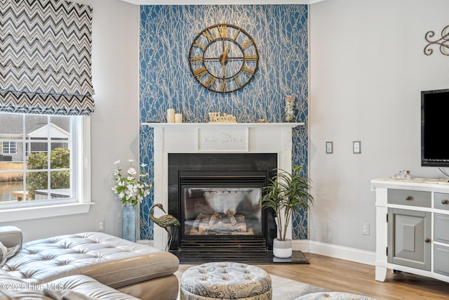 living area with a glass covered fireplace, wood finished floors, and baseboards