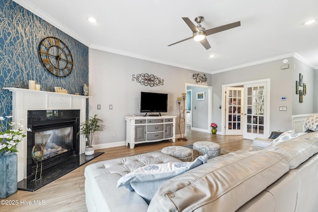 living room with baseboards, ceiling fan, an accent wall, and ornamental molding