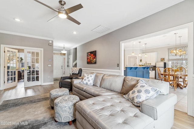 living room featuring visible vents, plenty of natural light, crown molding, and ceiling fan with notable chandelier