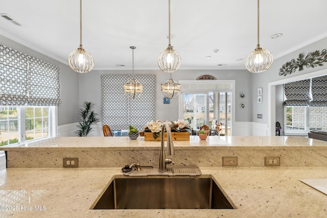 kitchen with light stone counters, visible vents, ornamental molding, and a sink