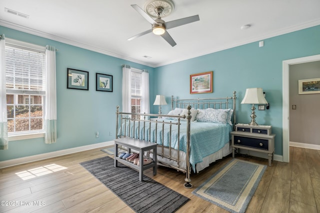 bedroom with crown molding, wood finished floors, and visible vents