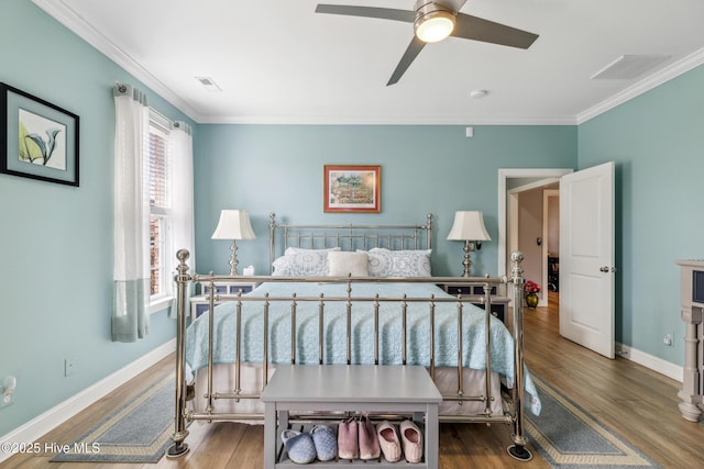 bedroom featuring visible vents, baseboards, wood finished floors, and crown molding