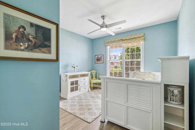 bedroom featuring light wood-style flooring, a ceiling fan, and visible vents