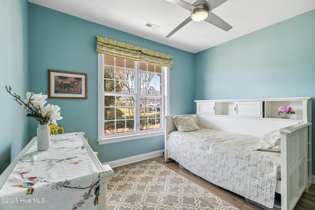 bedroom featuring visible vents, ceiling fan, baseboards, and wood finished floors