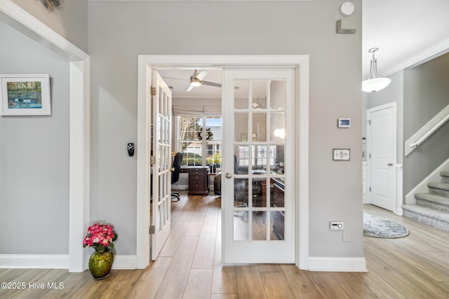 interior space featuring wood finished floors, baseboards, stairs, french doors, and crown molding