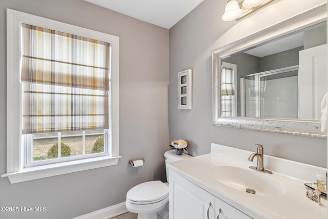 bathroom with vanity, a shower stall, toilet, and baseboards