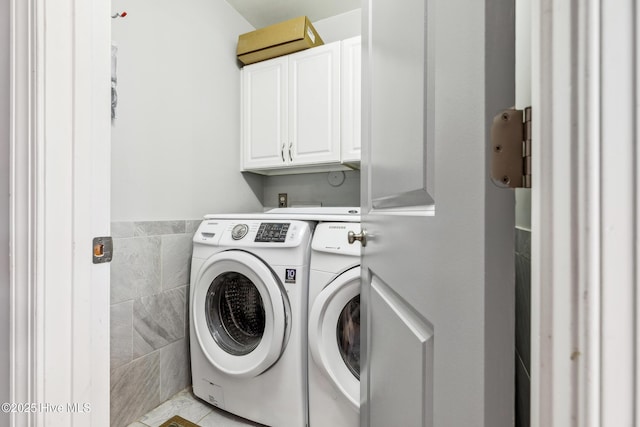 laundry area with washer and clothes dryer, cabinet space, and tile walls