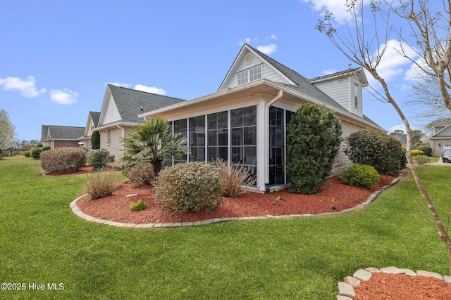 back of house with roof with shingles, a yard, and a sunroom