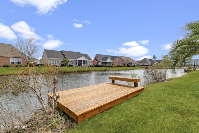 view of dock with a yard, a residential view, and a water view