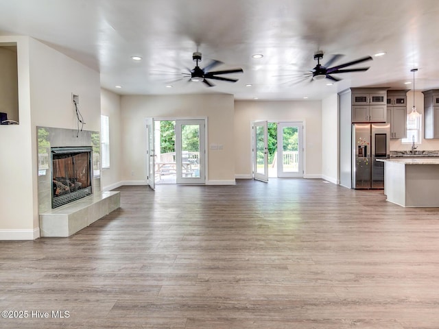 unfurnished living room with baseboards, recessed lighting, light wood-type flooring, and a premium fireplace