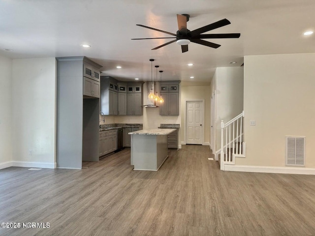 kitchen with visible vents, gray cabinets, a kitchen island, wood finished floors, and open floor plan