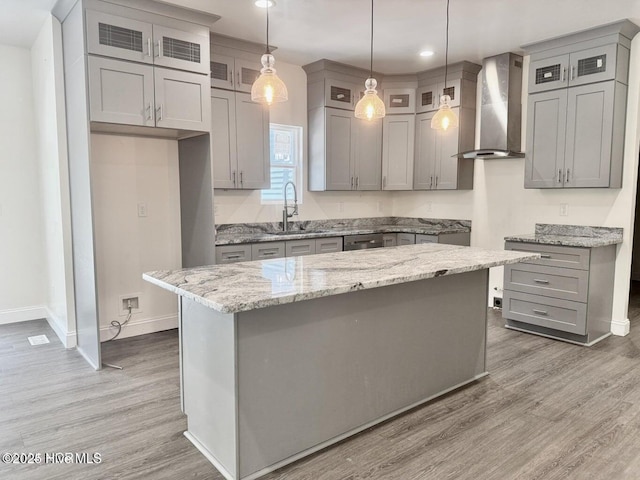 kitchen with gray cabinetry, wall chimney exhaust hood, light wood-style floors, and a sink