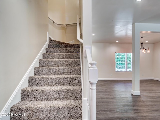 stairway with recessed lighting, wood finished floors, baseboards, and a chandelier