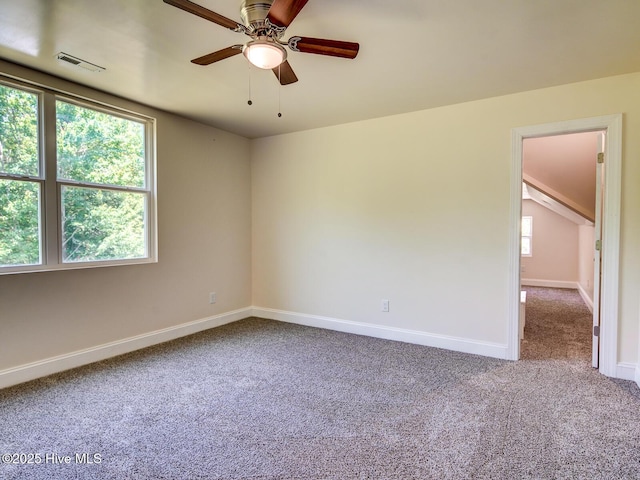 carpeted spare room with lofted ceiling, baseboards, visible vents, and ceiling fan