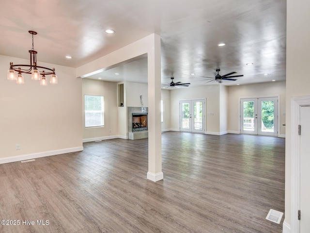 unfurnished living room with a fireplace, wood finished floors, plenty of natural light, and french doors