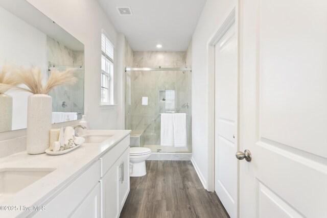 bathroom with a sink, a marble finish shower, toilet, and wood finished floors