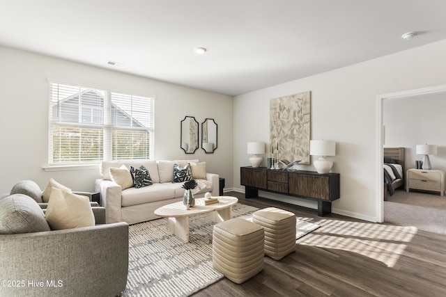 living room featuring visible vents, baseboards, and wood finished floors