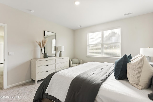 bedroom featuring visible vents, light colored carpet, and baseboards