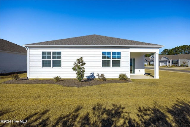 rear view of property featuring a shingled roof and a yard