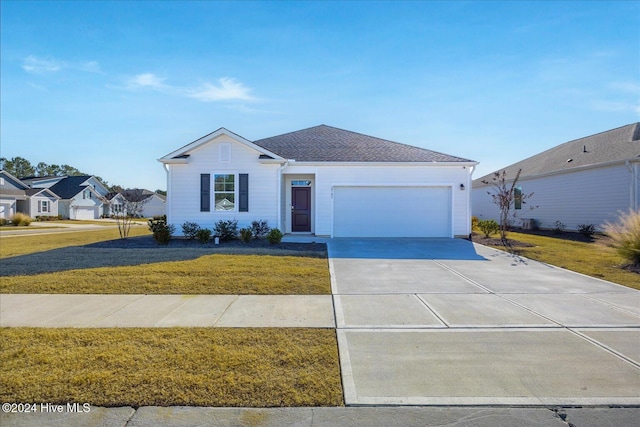 ranch-style home featuring an attached garage, roof with shingles, concrete driveway, and a front lawn