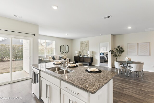 kitchen with visible vents, a sink, open floor plan, stone counters, and stainless steel dishwasher