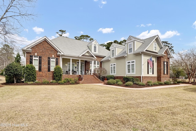 view of front facade with a front yard, a porch, and brick siding