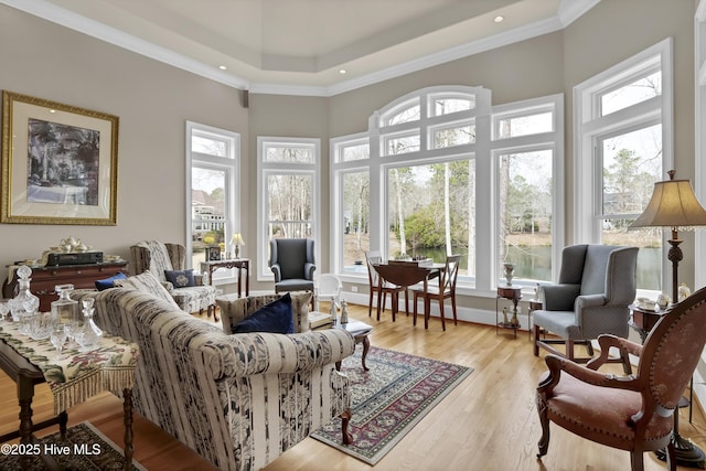 living room with a towering ceiling, light wood-style floors, and ornamental molding