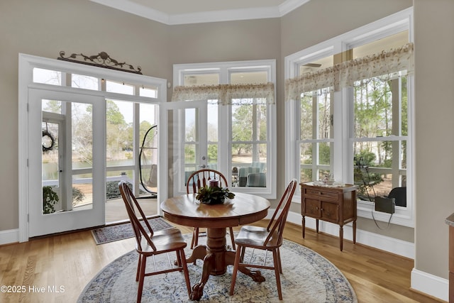 dining space featuring baseboards, light wood-style flooring, and ornamental molding