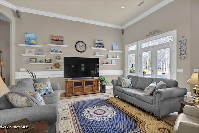 living area with wood finished floors, visible vents, and ornamental molding