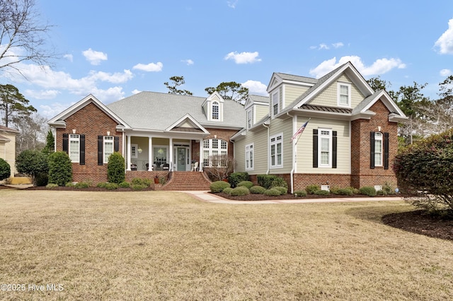 view of front of home with brick siding, a porch, and a front lawn