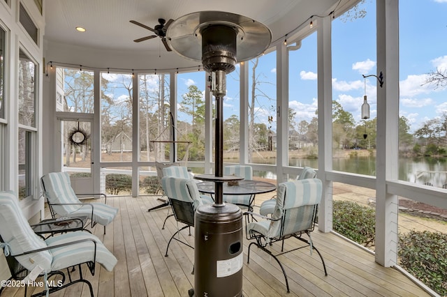 sunroom / solarium featuring a ceiling fan and a water view