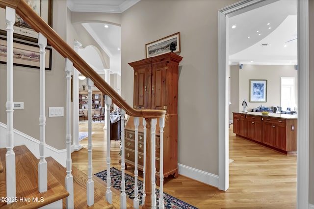 staircase with ornamental molding, wood finished floors, recessed lighting, arched walkways, and baseboards