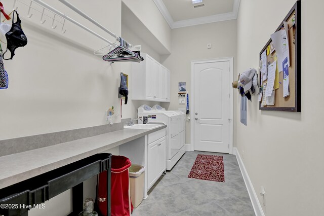 clothes washing area with crown molding, baseboards, washing machine and dryer, cabinet space, and a sink