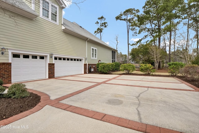 view of home's exterior featuring brick siding, driveway, a shingled roof, and an attached garage