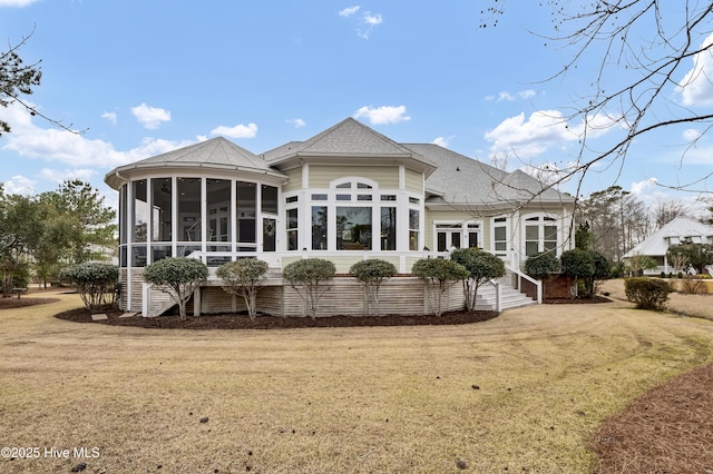 rear view of property featuring a yard, a shingled roof, and a sunroom