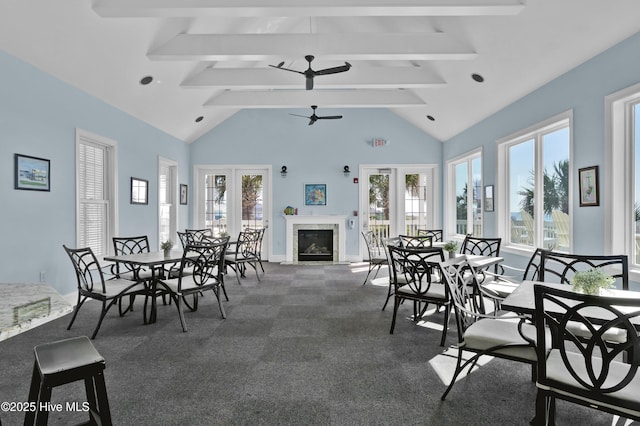 dining room featuring beamed ceiling, a ceiling fan, a high end fireplace, and carpet