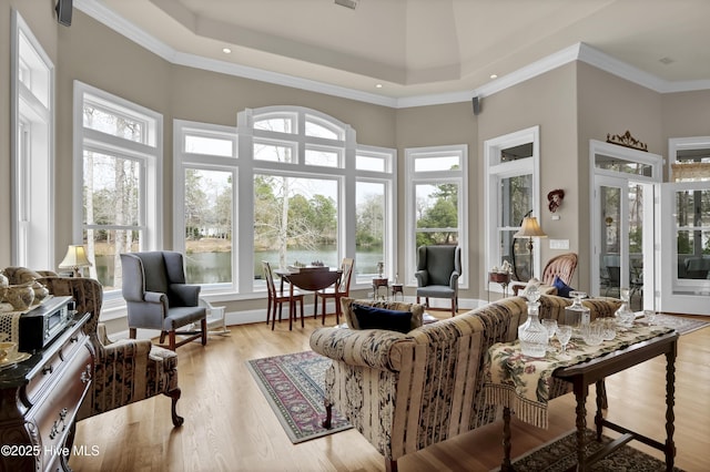 living room featuring crown molding, light wood-type flooring, and a high ceiling