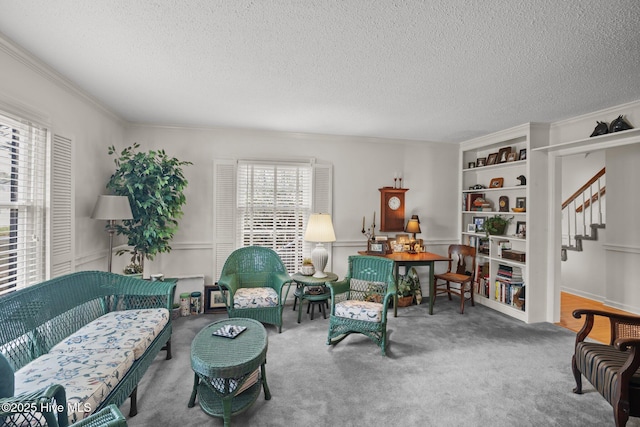 living area featuring ornamental molding, a textured ceiling, stairway, carpet, and wainscoting