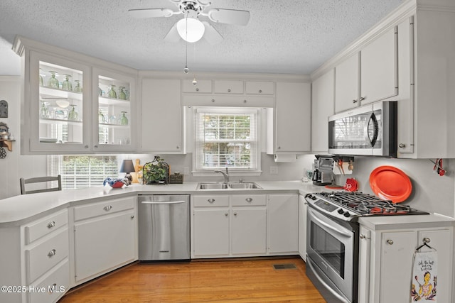 kitchen featuring visible vents, light countertops, light wood-style floors, stainless steel appliances, and a sink