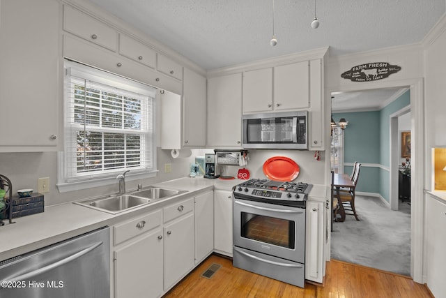 kitchen with a sink, white cabinetry, appliances with stainless steel finishes, and light countertops