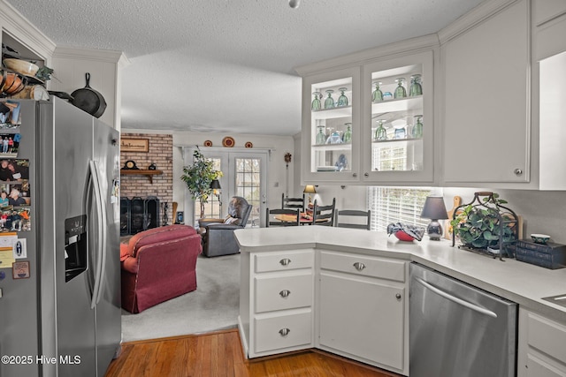 kitchen featuring open floor plan, light countertops, a peninsula, stainless steel appliances, and white cabinetry