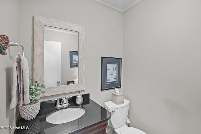 half bathroom with vanity, crown molding, and toilet