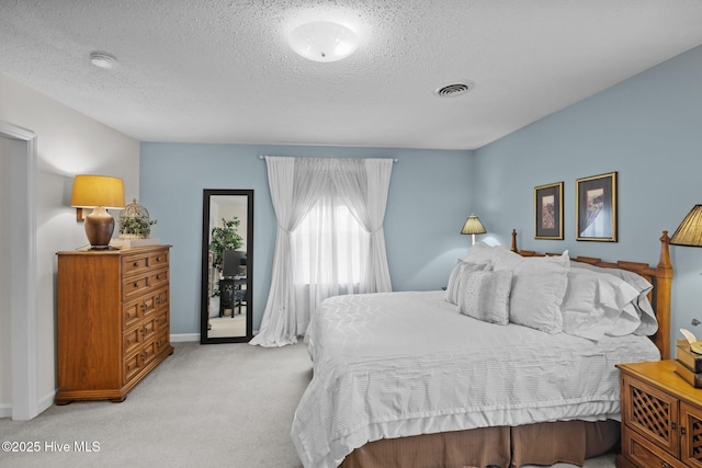 bedroom with a textured ceiling, baseboards, visible vents, and light carpet