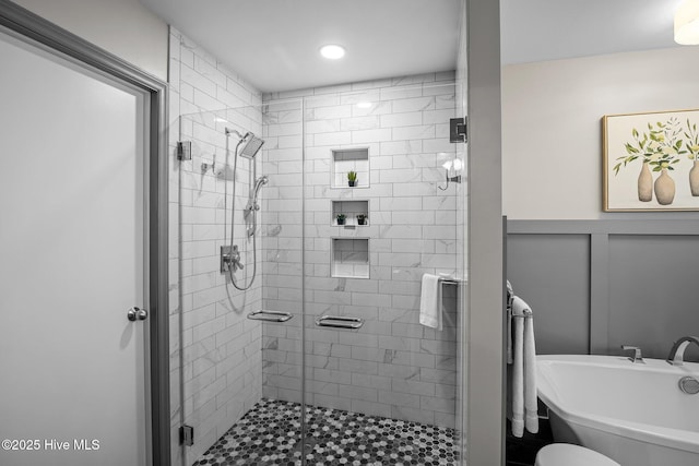 full bath with a decorative wall, a stall shower, a wainscoted wall, and a freestanding tub